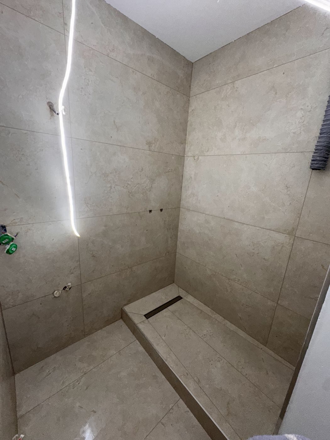 Douche à l'italienne carrelée grand format avec caniveau et niche lumineuse