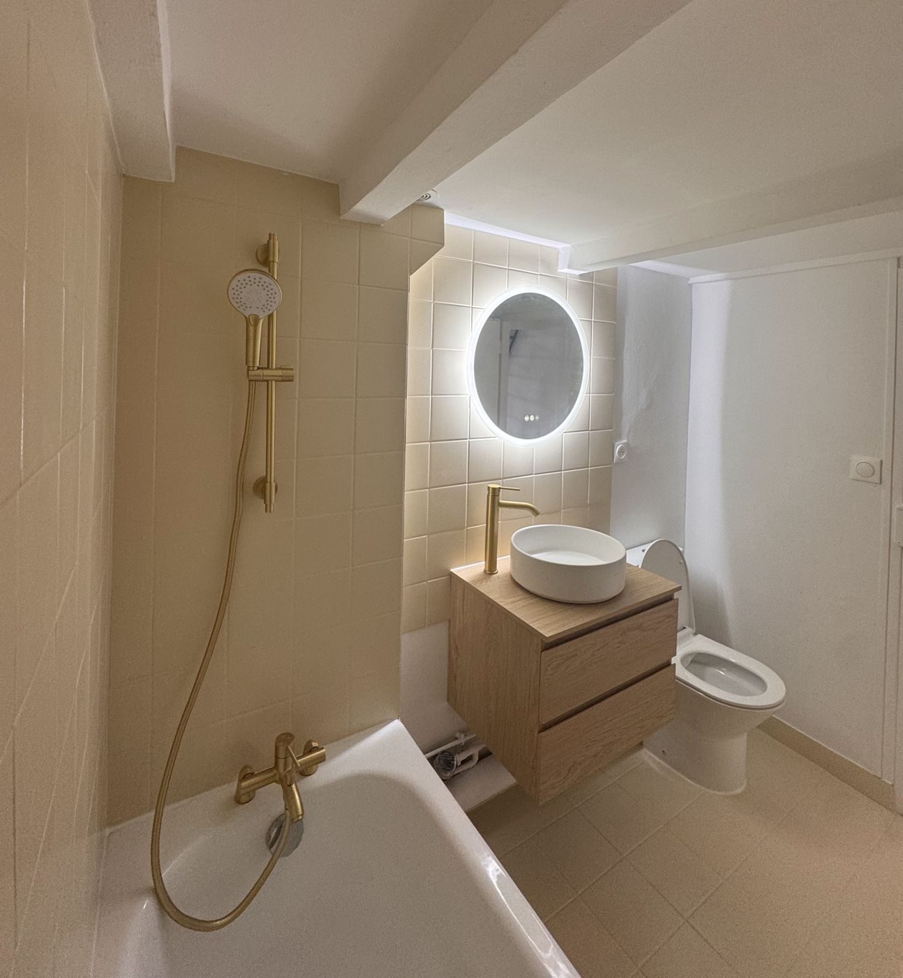 Seconde salle de bain rénovée : faïence claire, vasque à poser et miroir lumineux